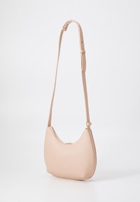 Borsa a spalla in pelle rosa pallido con forma curvata, tracolla regolabile e un dettaglio in zip dorata nella parte superiore. Texture liscia, design minimalista.