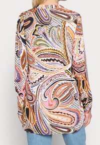 Blusa a maniche lunghe caratterizzata da un motivo paisley colorato in tonalità di rosa, arancio e verde su uno sfondo chiaro con una texture di tessuto liscia.