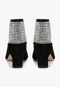 Zwarte suède enkellaarsjes met een blokhak, met een achterpaneel bedekt met zilveren strass-steentjes en een decoratief gouden accent.
