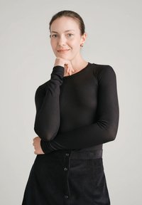 Czarny top z długim rękawem o fakturze prążkowanej, zestawiony z czarną spódnicą sztruksową z przodu ozdobioną guzikami i dopasowanym stanem.