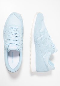 Baskets de sport bleu clair en daim, avec un système de laçage, un col rembourré et une semelle en caoutchouc blanc dotée d'un profil texturé.