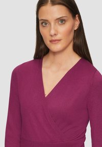 Maglione a collo a V, maniche lunghe, in tessuto a maglia viola intenso con stile aderente. Presenta delle leggere costine lungo i polsini e l'orlo.