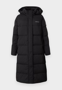 Black puffer coat, knee-length with a hood, quilted design, featuring a front zipper and logo on the chest. Textured, insulated fabric.