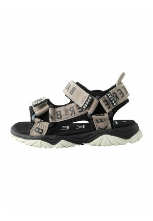 Sort og beige udendørs sandal med justerbare stofstropper og en robust hvid sål for bedre greb.
