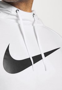 Biała bluza z kapturem wykonana z miękkiego materiału, z czarnym logo Nike w kształcie zygzaka. Posiada kaptur ze sznurkiem i gładką fakturę.