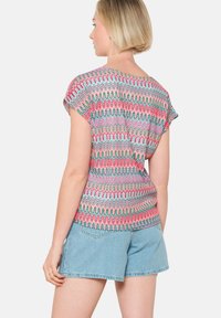 Kleurvolle gebreide top met kapmouwen, met een zigzagpatroon in roze, groen en grijs. Gecombineerd met denimshorts voor een ontspannen fit.