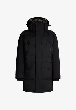 Zwarte gewatteerde parka met een hoge kraag, voorrits, twee met rits sluitende borstzakken en twee grote voorzakken. Zachte binnenvoering.