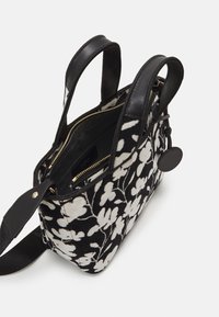 Černobílá kabelka s květinovým vzorem, koženými akcenty, dvojitými rukojeťmi, zipovým uzávěrem a prostorným interiérem.