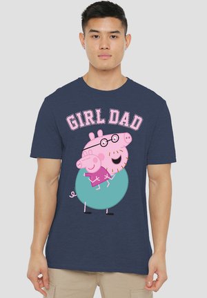 Navy blue t-shirt featuring cartoon pigs and the text "GIRL DAD" in pink. The design includes details like glasses and a round shape on one pig.