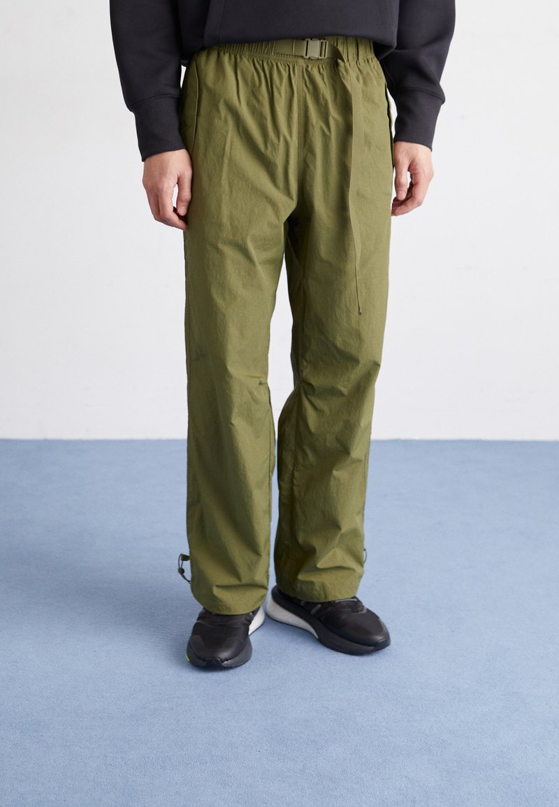 Grüne leichte Hose mit elastischem Bund und verstellbarem Gürtel. Flaches Vorderdesign mit subtiler Textur und seitlichen Taschen.