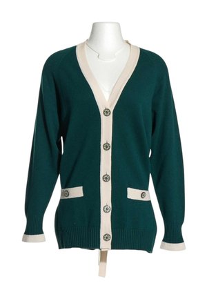 Cardigan vert foncé avec bordure beige, cinq boutons décoratifs sur le devant, deux poches avant avec un bouton chacune, et manches longues.