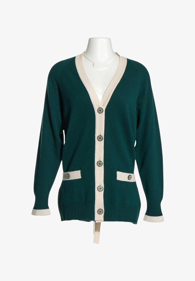 Cardigan vert foncé avec bordure beige, cinq boutons décoratifs sur le devant, deux poches avant avec un bouton chacune, et manches longues.