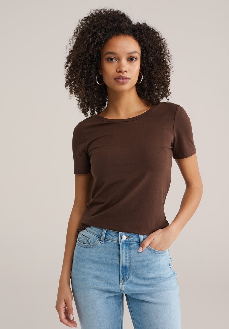 Bruin T-shirt met korte mouwen gemaakt van zacht, rekbaar materiaal. Getailleerd ontwerp met een ronde hals, gecombineerd met lichtblauwe jeans met een hoge taille.