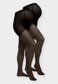 Deux paires de jambes portant des bas noirs transparents montants jusqu'aux cuisses avec des hanches renforcées, se tenant devant un fond clair uni.