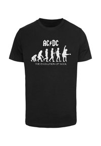 Svart bomull t-skjorte med hvit grafisk trykk av evolusjonsfigurer med instrumenter og teksten "AC/DC THE EVOLUTION OF ROCK."