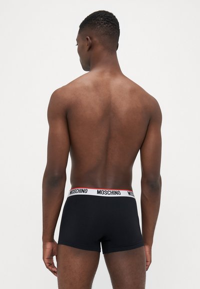 Black boxer briefs with a white elastic waistband featuring red "MOSCHINO" branding. Material appears soft, fitted, and smooth in texture.
