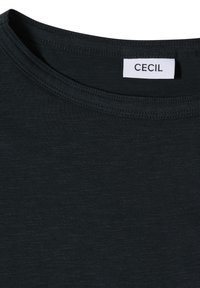 T-shirt noir à col rond avec des coutures visibles et une étiquette blanche cousue à l'intérieur du col affichant le nom de la marque "CECIL".