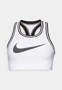Hvit sports-BH laget av teksturert materiale med svarte detaljer. Har et racerback-design og en svart Nike-logo med prikkete mønster.