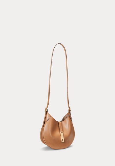 Hellbraune Lederschultertasche mit geschwungener Form, verstellbarem Riemen und goldfarbenem Verschluss mit kleinem geprägtem Logo.