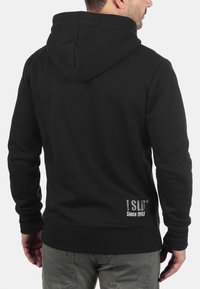 Zwarte hoodie van katoen. Voorzien van een buidelzak en een logo op de achterkant. Geribbelde manchetten en onderrand, zachte textuur.