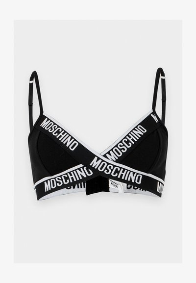 Μαύρο σουτιέν bralette με λεπτές ρυθμιζόμενες τιράντες και λευκές ελαστικές ταινίες που διασταυρώνονται μπροστά, με επαναλαμβανόμενο λογότυπο Moschino σε έντονα γράμματα.