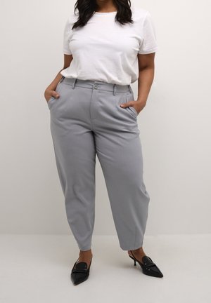 Lysegrå, tapered bukser med en glat struktur, to frontlommer og knaplukning, kombineret med en hvid t-shirt og sorte hæle.