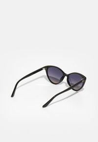 Lunettes de soleil noires en forme d'œil de chat avec des verres violets dégradés, finition brillante et branches fines. Accents en argent remarquables aux charnières.