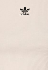 Biele pruhované tielko s malým čiernym logom Adidas na hrudi. Tkanina je hladká s priliehavým strihom a nenápadnou textúrou.