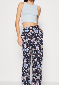 Haut court côtelé bleu clair associé à un pantalon large bleu marine à motifs floraux avec des fleurs roses et bleues, en tissu lisse, avec des poches latérales.