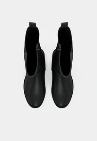Čierne členkové topánky z hladkého, vodeodolného materiálu s okrúhlou špičkou, elastickými panelmi na bokoch a pútkom vzadu.