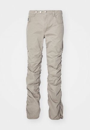 Pantalones de tela texturada en color beige con un diseño fruncido, que cuentan con una bragueta de botón, cinco bolsillos y un corte de pierna recta.
