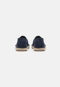 Sötétkék, velúr espadrilles, fonott jutaszóléval. Simább textúrájú, kerek orrú és nyitott hátsó kialakítású.