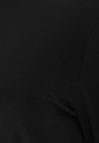 Schwarzer Stoff, der eine Nahaufnahme der glatten Textur und kurven zeigt, was auf ein Kleidungsdesign mit sanften Drapierungen und minimalen Details hindeutet.