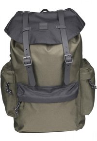 Sac à dos vert foncé avec un rabat, des bretelles noires et de multiples poches. Présente un matériau robuste et des textures contrastées.