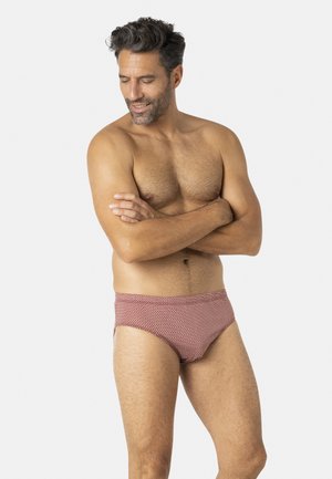 Maillot de bain slip rouge et blanc à motifs avec une taille haute. Le tissu semble lisse, ajusté et confortable. Le design présente un imprimé géométrique.