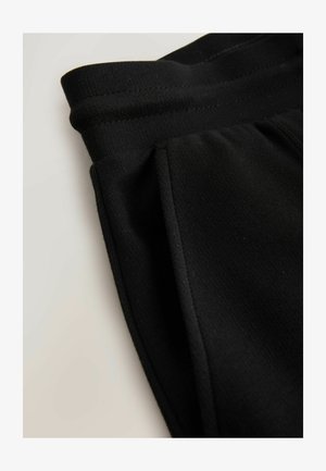 Svarta träningsbyxor med en slät textur, elastisk midjeresår och sidofickor, med en enkel design och en kroppsformad silhuett.