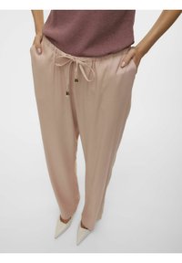 Pantalons à cordon de serrage de couleur rose clair, avec une coupe décontractée, présentant des accessoires en métal doré et une texture de tissu lisse.