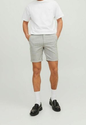 Shorts gris à carreaux avec une coupe ajustée, dotés d'un devant plat et de poches latérales. Associés à un t-shirt blanc uni et des mocassins noirs.