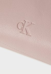 Portofel roz din piele, cu o suprafață texturată. Are logo-ul "ck" embosat și cusături vizibile pe margine.