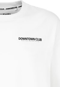 Weißes Sweatshirt mit rundem Halsausschnitt, langen Ärmeln und einem schwarzen "DOWNTOWN CLUB"-Logo auf der Brust, darunter zusätzlicher Text.