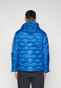 Μπλε μπουφάν puffer με σχεδιασμό καπιτονέ και κουκούλα. Διαθέτει υφασμάτινη υφή με ομαλή επιφάνεια, ορατή ραφή και λάστιχα στις μανσέτες.