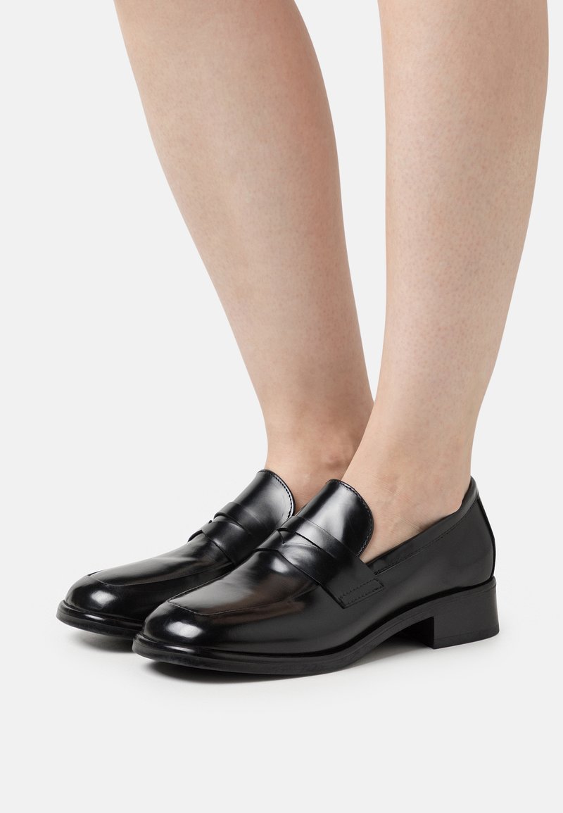 Sorte læder loafers med en glat finish, lav blokhæl og to dekorative forreste bånd. Designet til nemt at tage på.