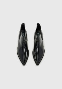Black leather ankle boots with a pointed toe, smooth texture, and elastic side panels. Features a logo on the interior. Angular design.