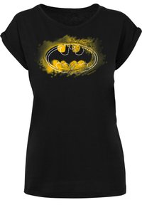 Black t-shirt made of soft fabric with a loose fit, featuring a yellow Batman logo graphic in a distressed style. Short rolled sleeves.