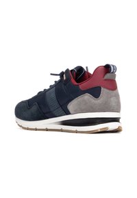 Zapatilla deportiva en tonos azul marino y gris, confeccionada con materiales de ante y malla. Presenta un diseño de cordones, cuello acolchado y suela de goma texturizada.