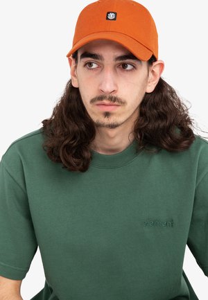 Camiseta de algodón verde con mangas cortas y logo "element" bordado. Gorra naranja con un parche de logo negro que muestra un diseño estructurado.