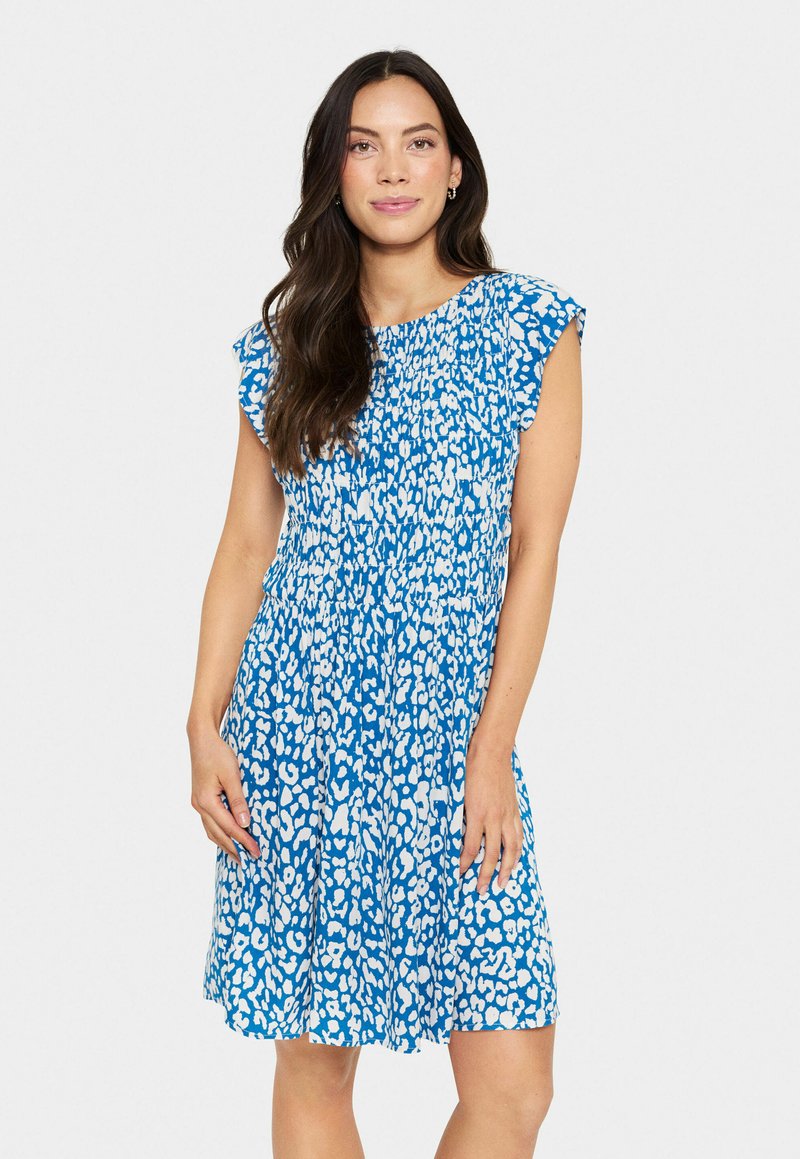 Robe bleue avec un motif animalier blanc, manches courtes volantées, corsage smocké et coupe décontractée, conçue pour le confort et le style.
