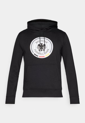 Melnā kapuce ar priekšējo kabatu, uz kura atrodas apļveida logotips ar ērgli, ko ieskauj krāsainas svītras un teksts "Deutscher Fußball-Bund."