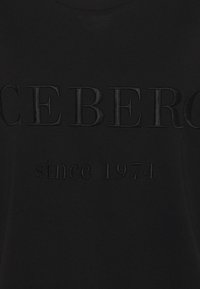 Camiseta negra con texto en relieve: "CEBERO" y "desde 1974". Tejido suave con una textura sutil y lisa, y cuello redondo.
