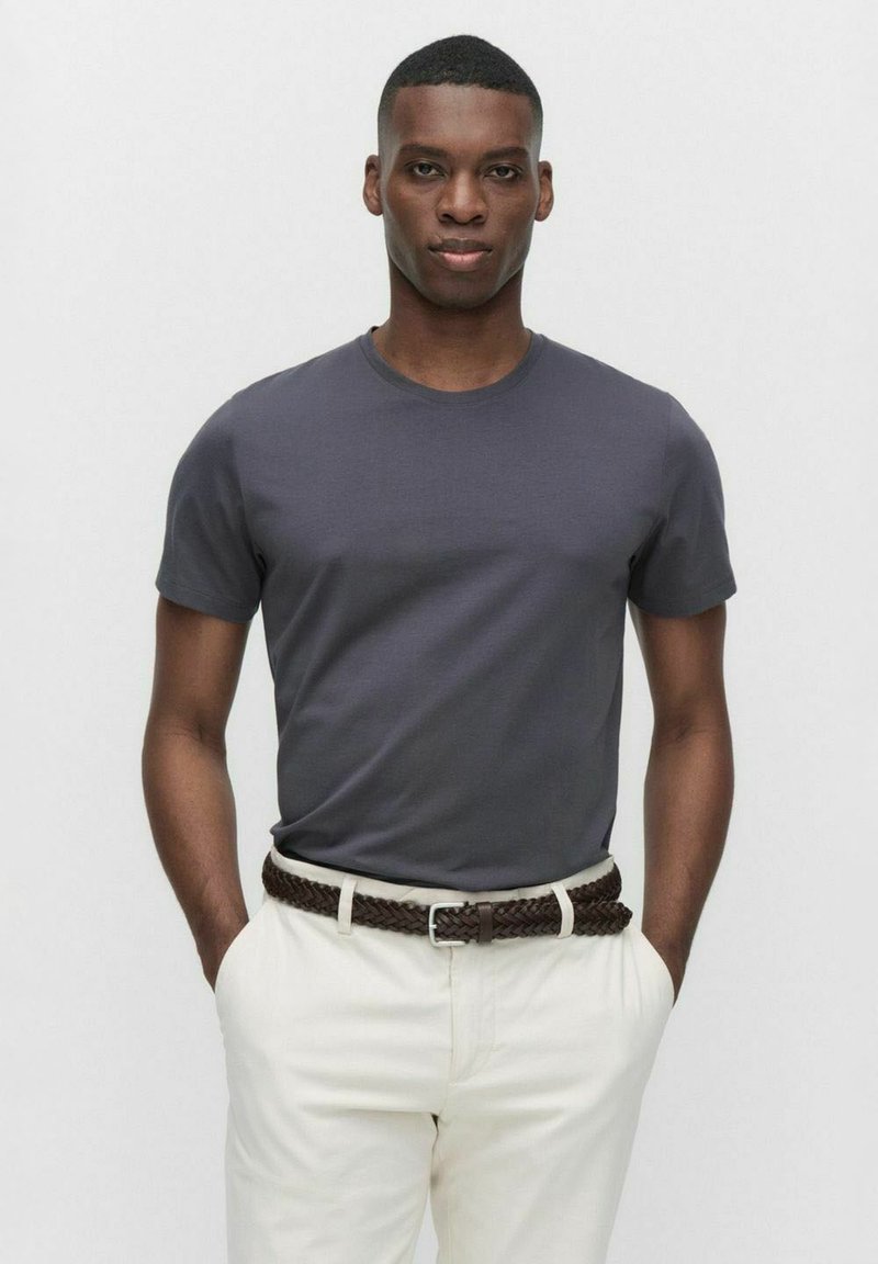 Grijze t-shirt met korte mouwen en een ronde hals, gecombineerd met beige broek en een gevlochten bruine riem. Glad oppervlak, eenvoudige pasvorm.